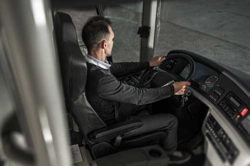 A bus driver sitting in a comfortable driver's seat.